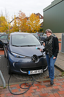 Frau Schäfer neben ihrem E-Auto