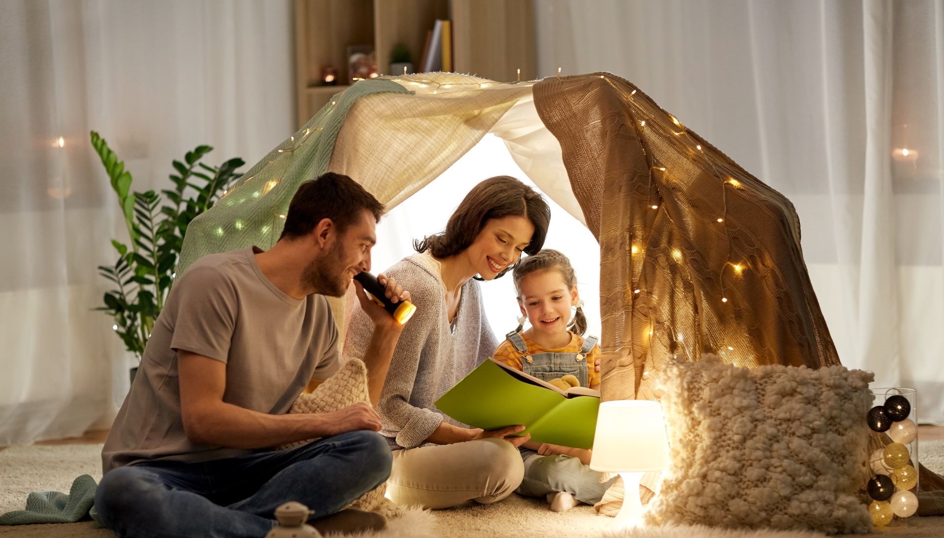 Familie hat sich eine kuschelige Höhle gebaut und und liest ein Buch